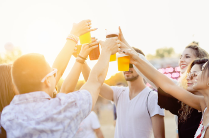 Six people cheering their drinks at an out door event.